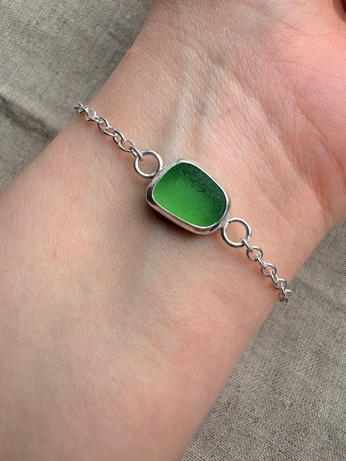 Green gemstone bracelet on a wrist with a neutral background